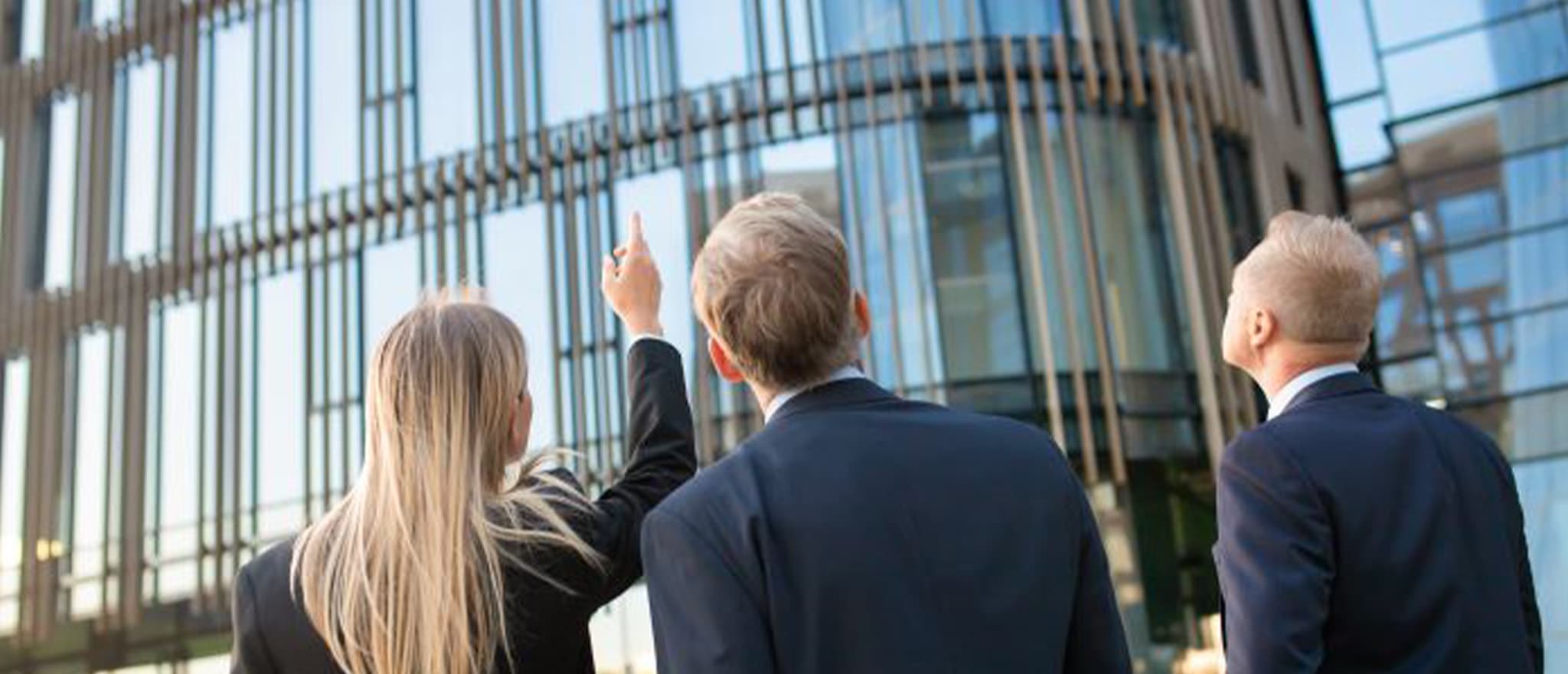 Three individuals outside a commercial property looking up at building