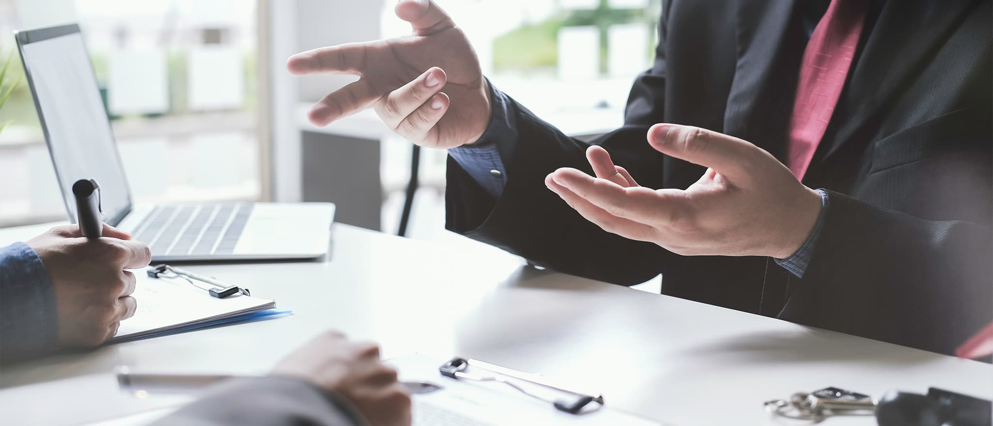 Three individual's hands around a table having a discussion