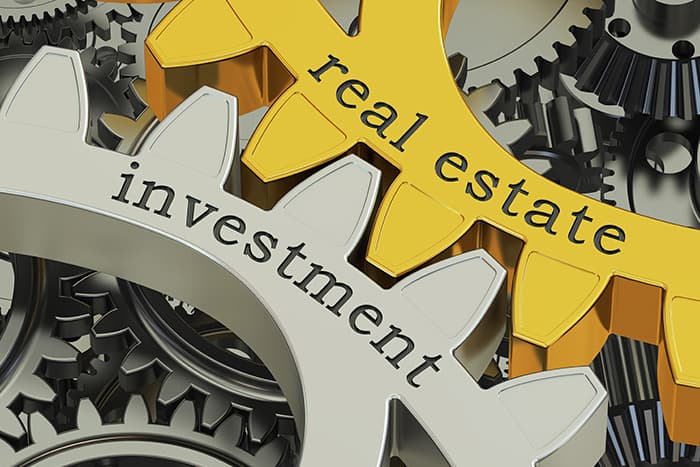Visual of gears with the words real estate and investment written on them