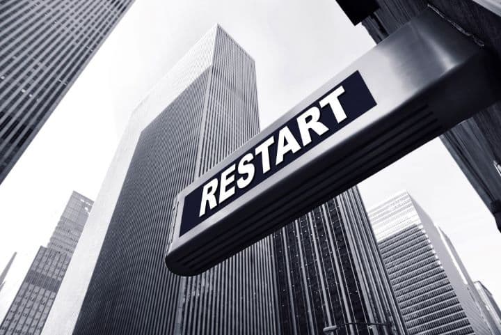 A sign that says restart with a city view in the background