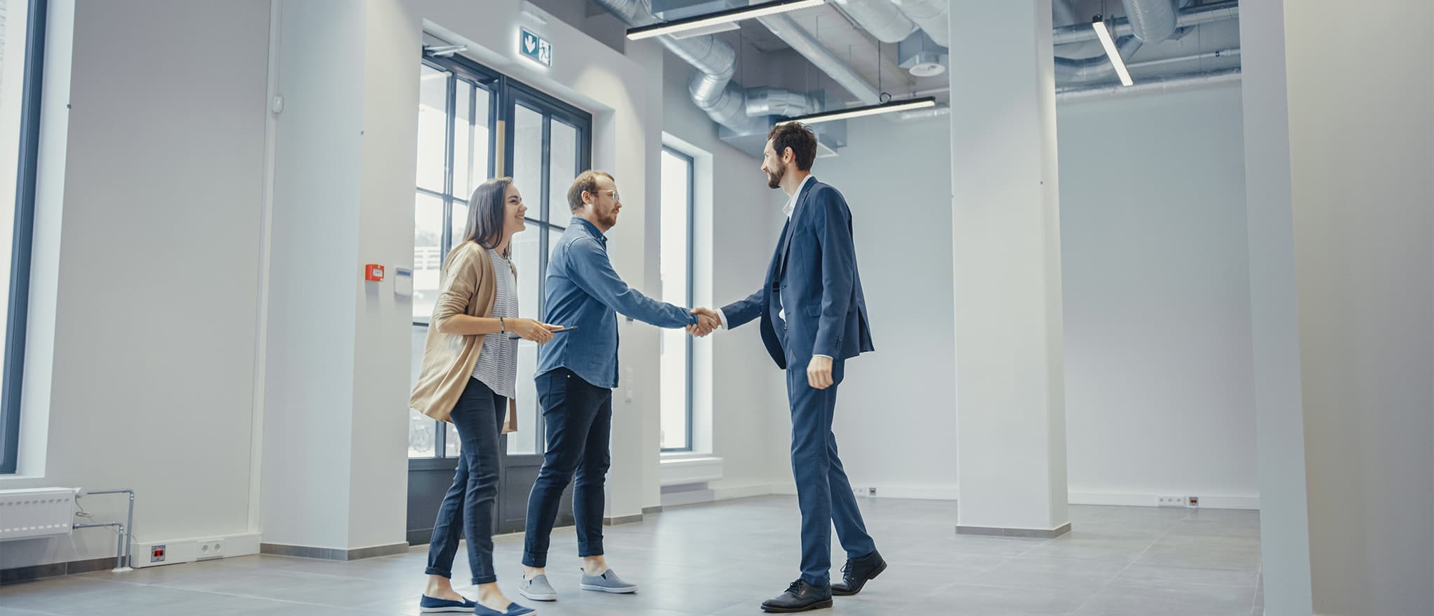 Three individuals in a commercial space with two of them shaking hands