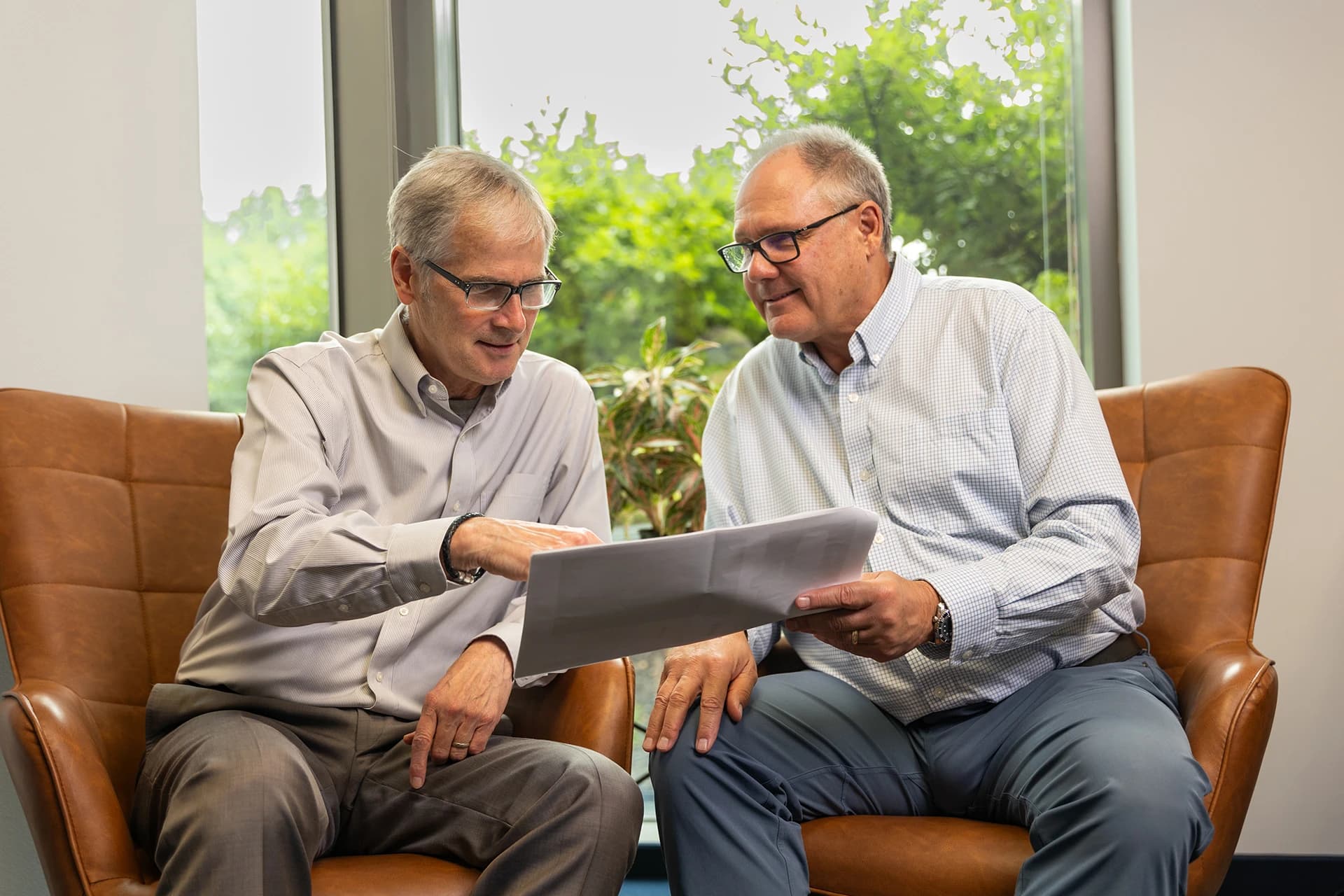 Two men sitting on chairs talking about commercial properties