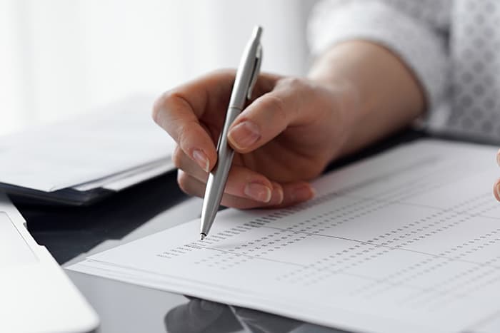 a hand writing with a pen on a piece of paper