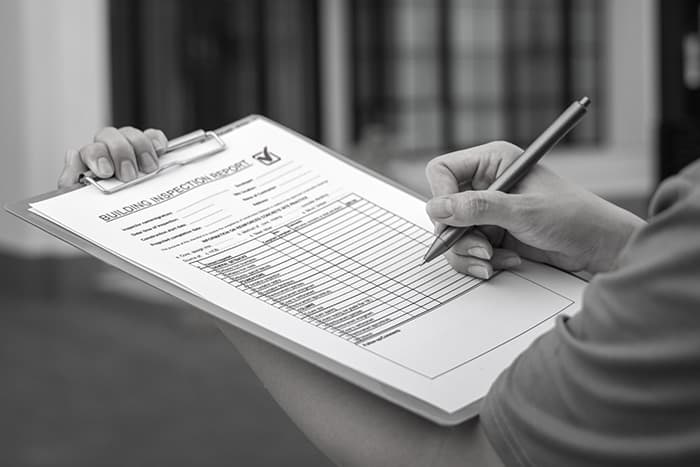 person writing on a building inspection report