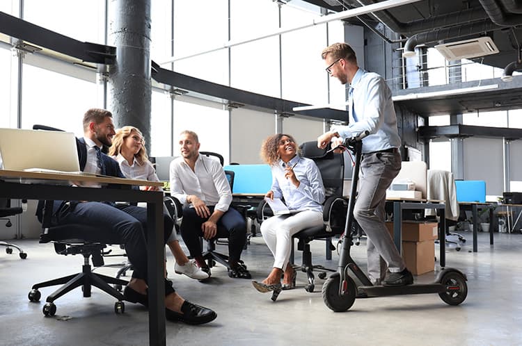 Five individuals having a discussion with one being on a scooter
