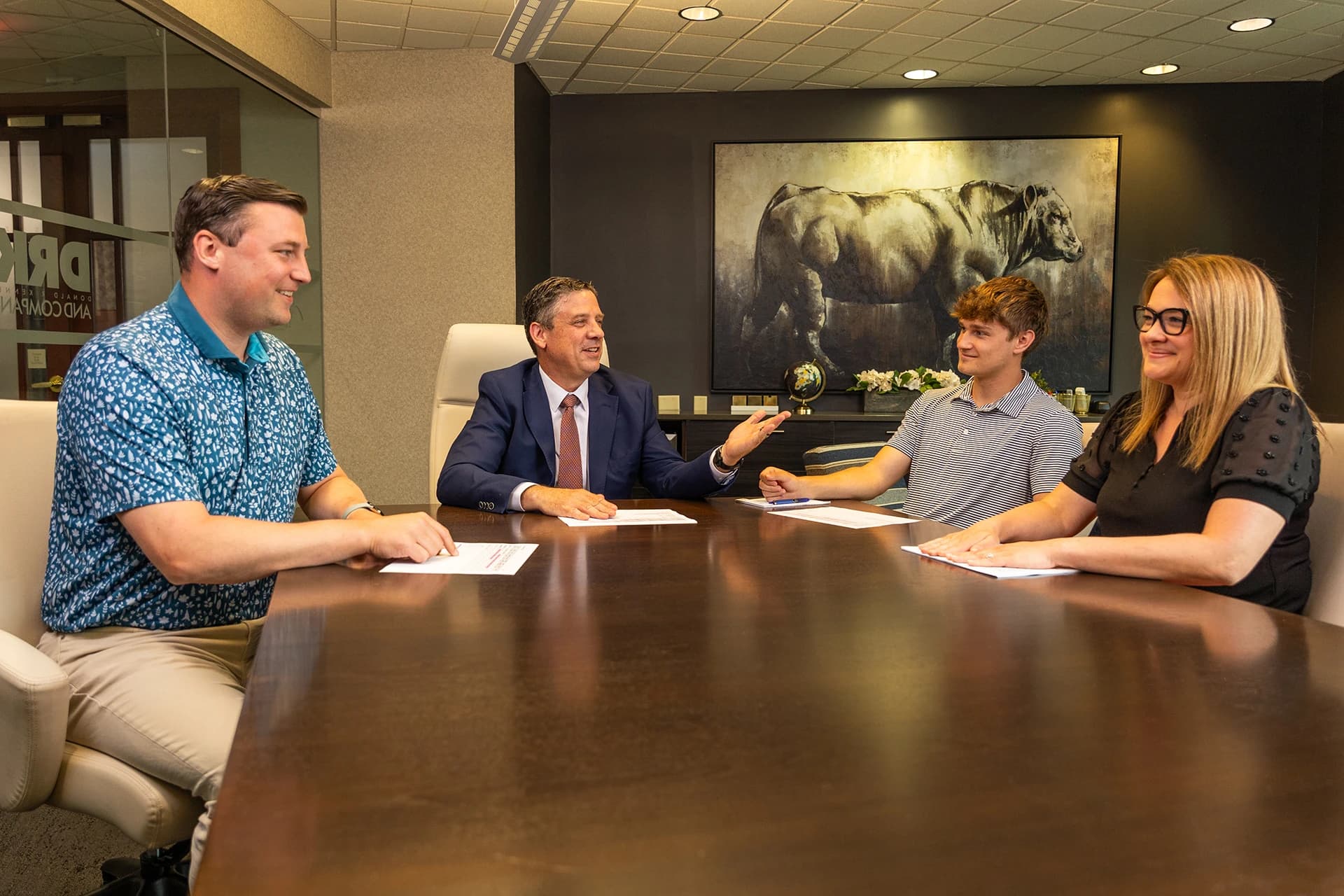 Three men and one woman talking in a conference room