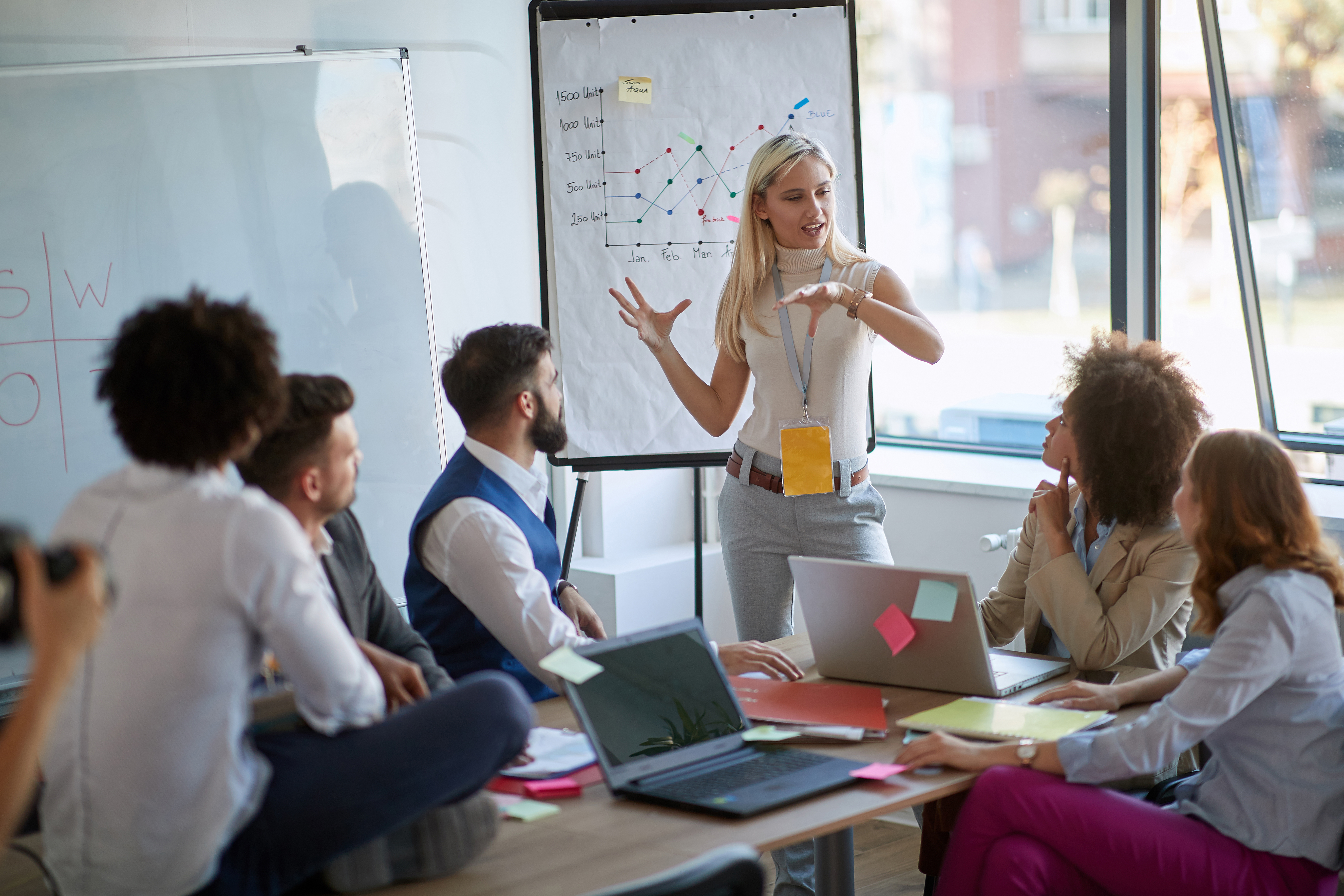 Image of a woman presenting at a board in a conference room.