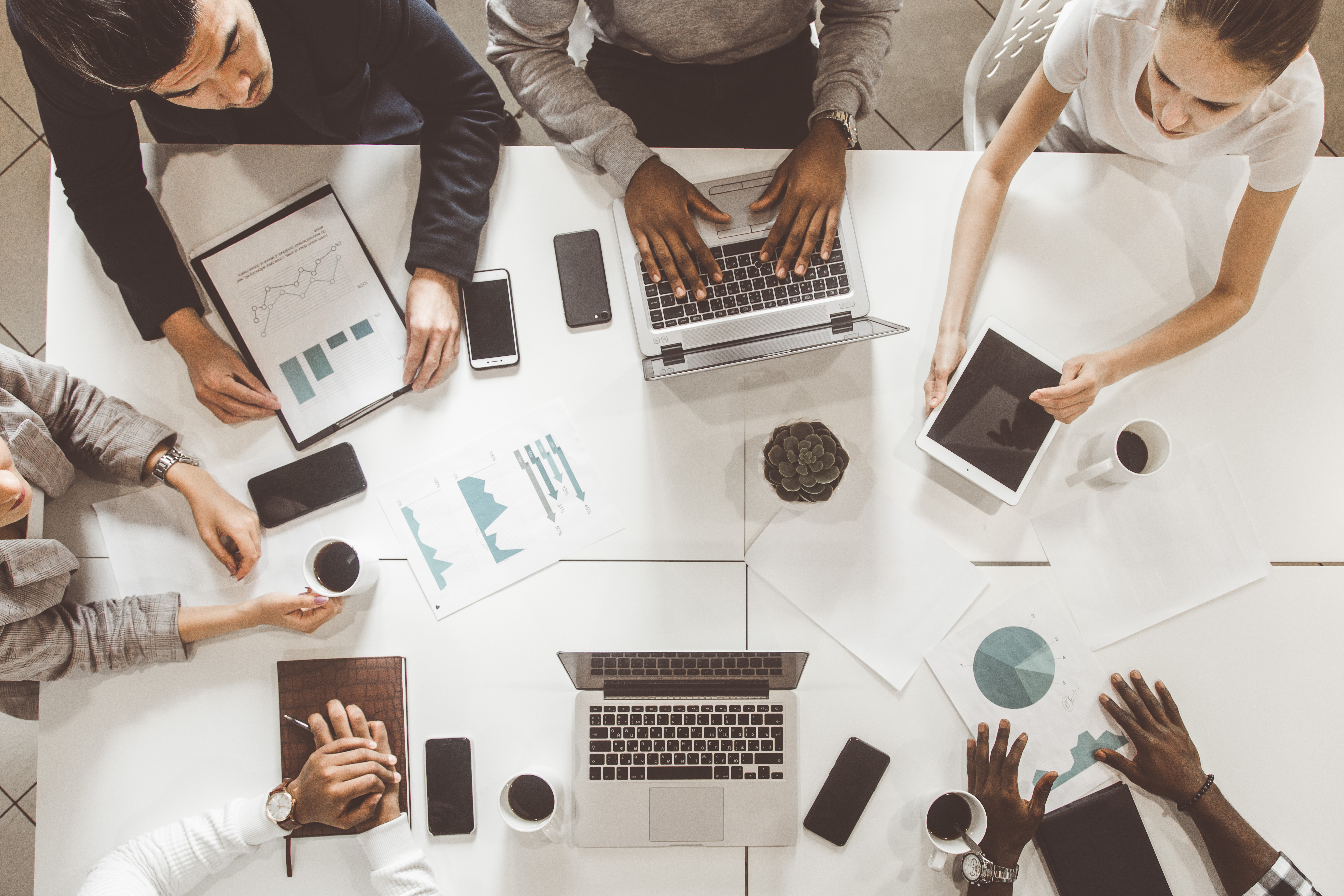 Image of people with papers and laptops working around a table.