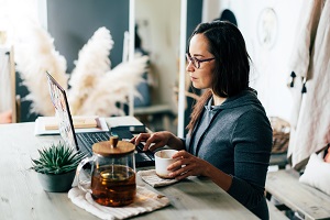 Image of a woman sitting at a desk looking at a laptop.