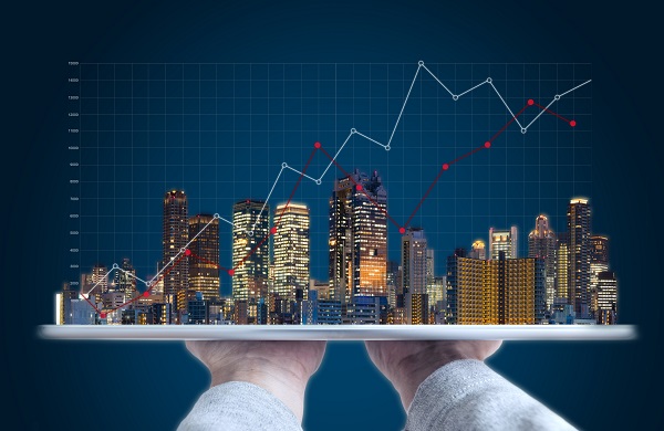 Image of hands holding a city skyline against the backdrop of a graph.