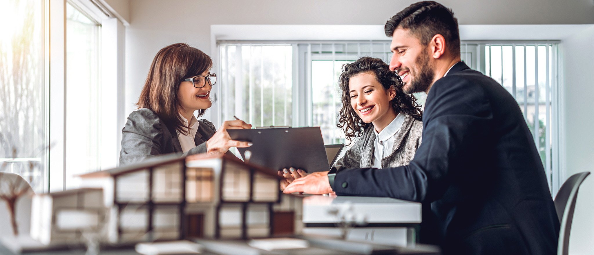 Side view of young happy family sitting in consulting office, making an investment property purchase.